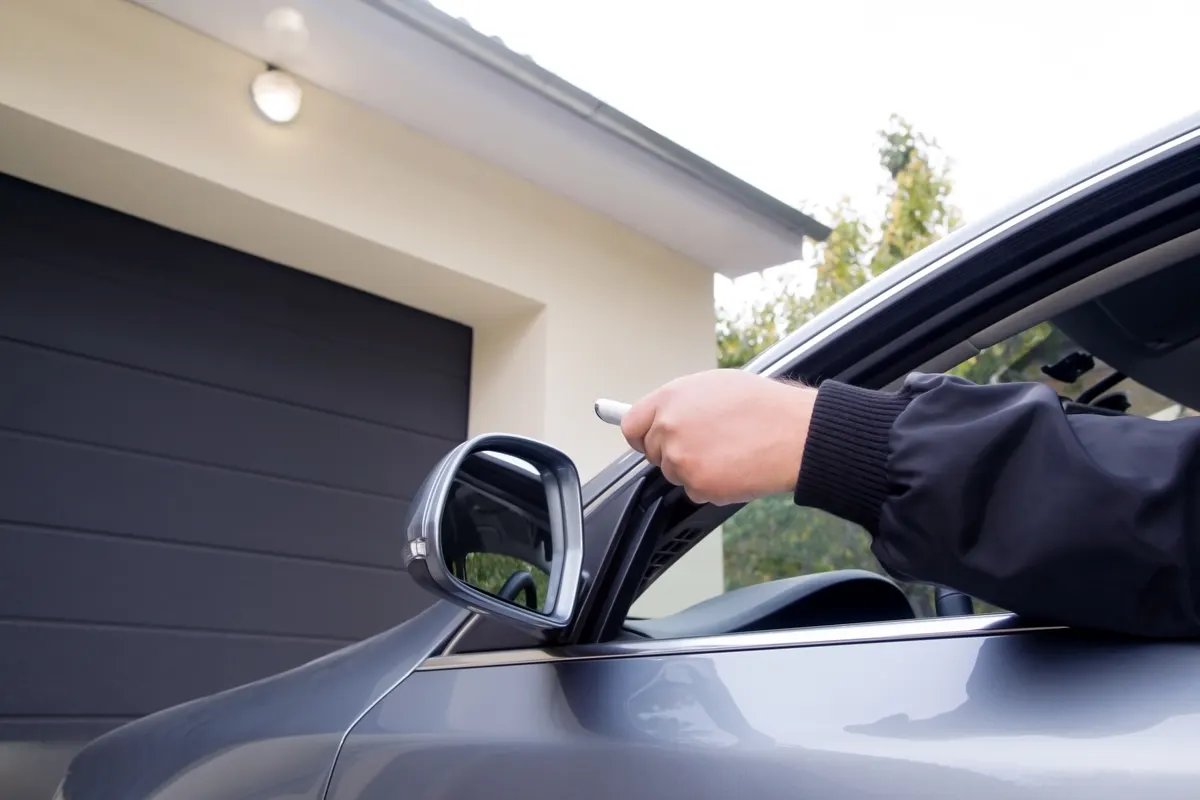 Driver opening a garage door with a remote